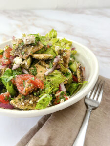 A homemade Fattoush salad with crisp pita chips, tomatoes, cucumbers, and chopped herbs