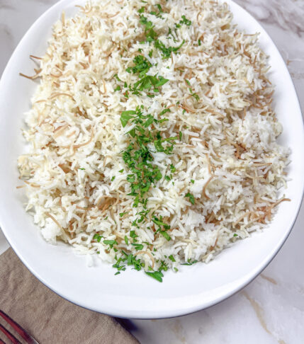 A simple plate of rice vermicelli noodles topped with chopped fresh parsley.