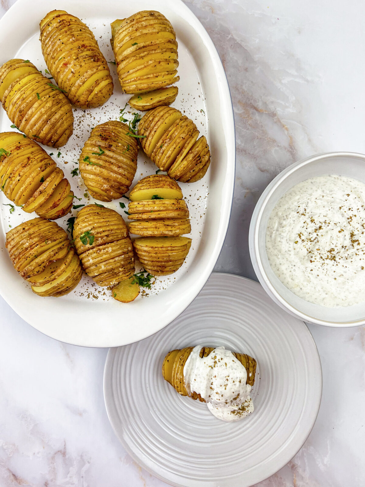 A close-up of a delicious hassle potato dish with creamy yogurt sauce and zaatar seasoning.