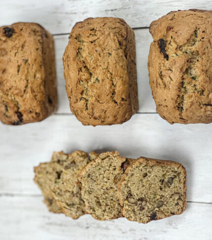 Three mini loaves of freshly baked zucchini bread with a few slices laid out