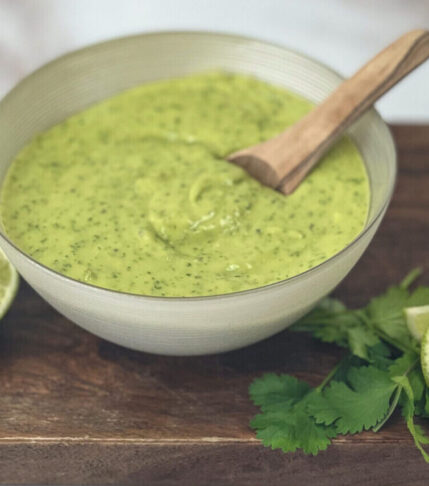 A bowl of creamy Avocado Lime Dressing garnished with fresh lime slices, ready to elevate your dishes with its tangy and refreshing flavors.