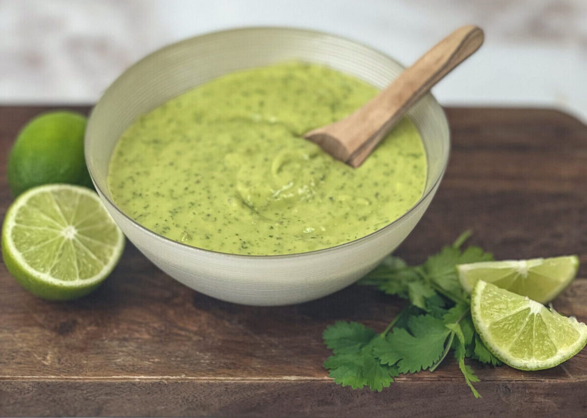 A bowl of creamy Avocado Lime Dressing garnished with fresh lime slices, ready to elevate your dishes with its tangy and refreshing flavors.