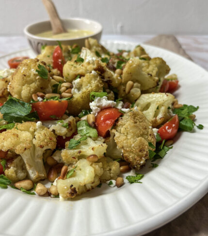 A colorful plate of Mediterranean Roasted Cauliflower Salad with Tomatoes and Feta Cheese.