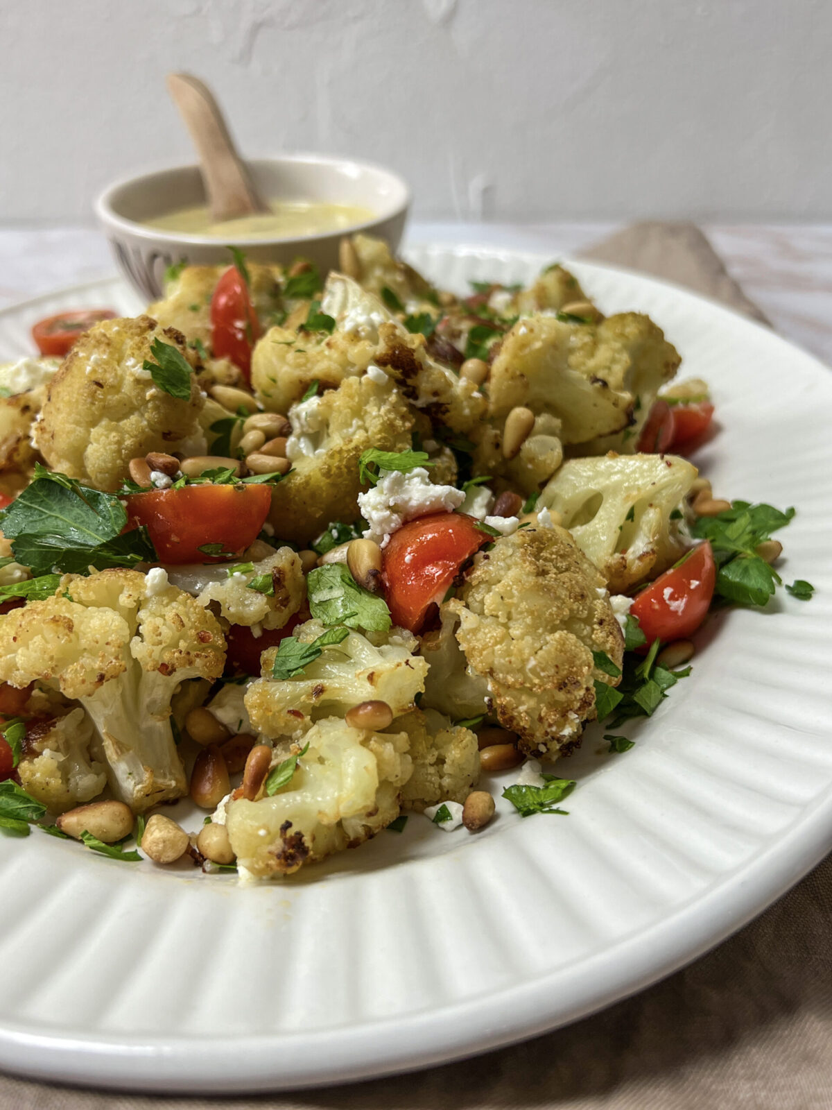 A colorful plate of Mediterranean Roasted Cauliflower Salad with Tomatoes and Feta Cheese.