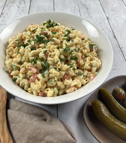 Final bowl of vibrant, creamy Deli-style Macaroni Salad, garnished with fresh herbs.