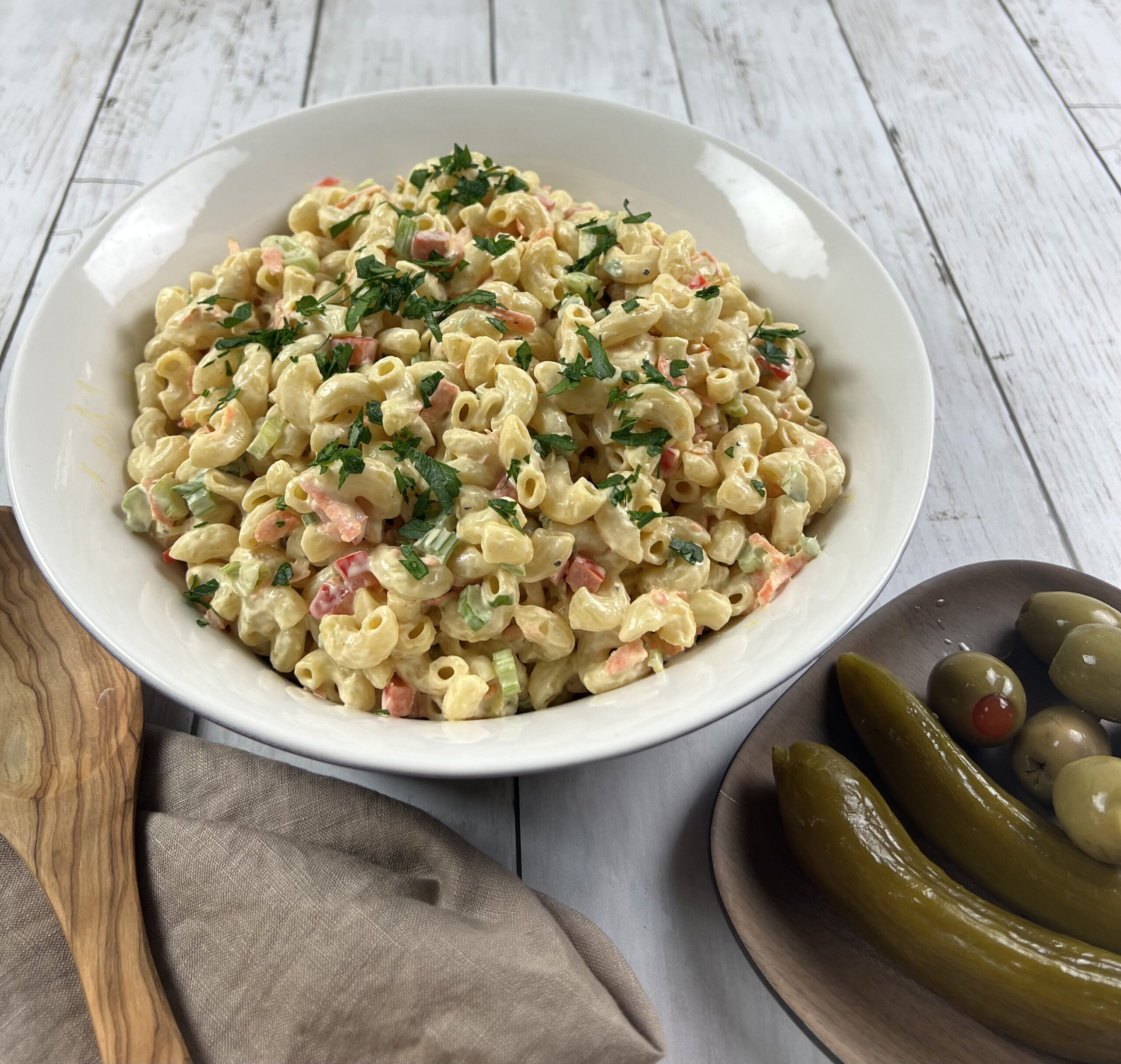 Final bowl of vibrant, creamy Deli-style Macaroni Salad, garnished with fresh herbs.