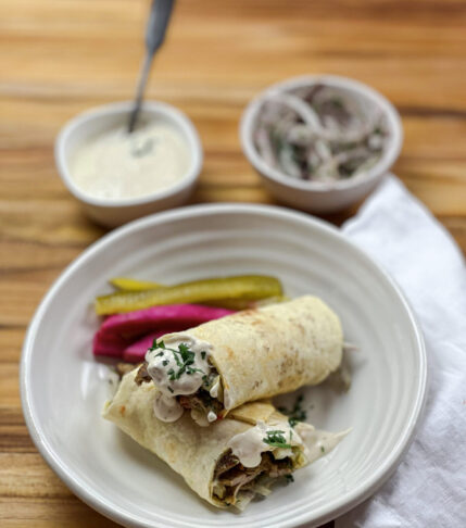 A delicious homemade shawarma wrap with sliced chicken, vegetables, and tzatziki sauce wrapped in a warm pita bread