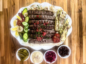 Golden-browned Kofta Kebabs on a platter, garnished with fresh herbs and accompanied by traditional Middle Eastern sides.