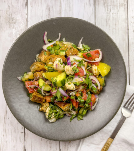 A vibrant bowl of Tomato Panzanella Salad garnished with fresh basil.