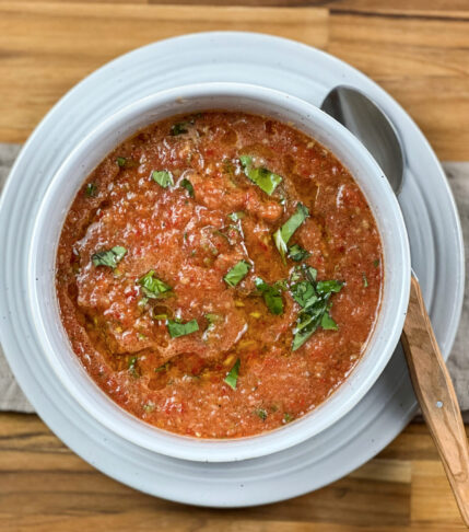 A vibrant bowl of homemade Gazpacho soup garnished with fresh basil.