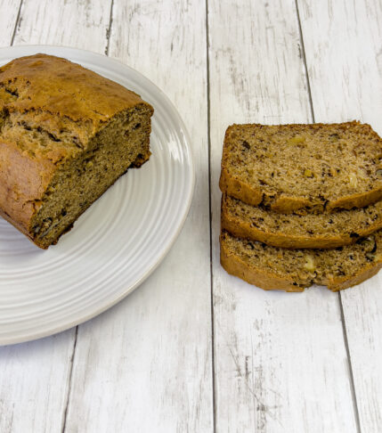 Freshly baked banana bread sliced on a cutting board.