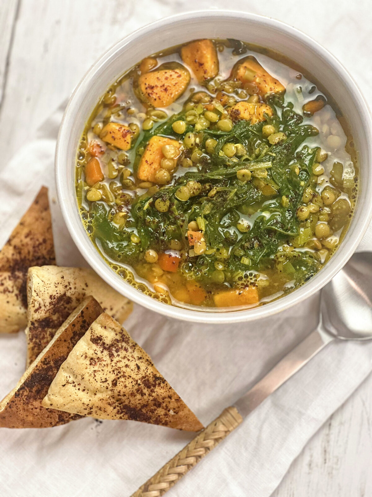 Bowl of Lentil Soup with Kale and Sweet Potatoes, accompanied by sliced pita bread.