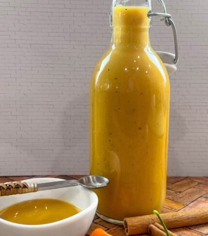 Bottle of homemade Mango Habanero Hot Sauce next to a small bowl filled with vibrant sauce.