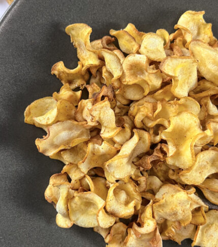 A plate overflowing with crispy, golden parsnip chips, seasoned to perfection and ready to be enjoyed as a healthy snack.