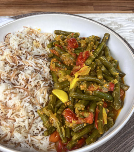 A delectable plate featuring half braised green beans and half rice vermicelli, offering a harmonious blend of vibrant colors and textures.