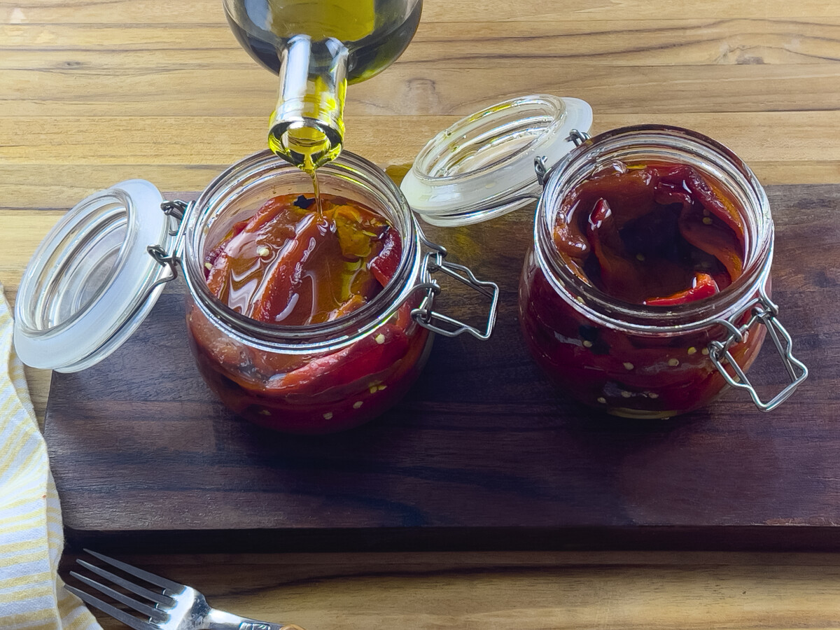 wo glass jars filled with charred bell peppers preserved in olive oil.