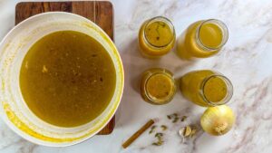 Lamb broth pot alongside three jars filled with rich, healthy Mediterranean lamb broth.