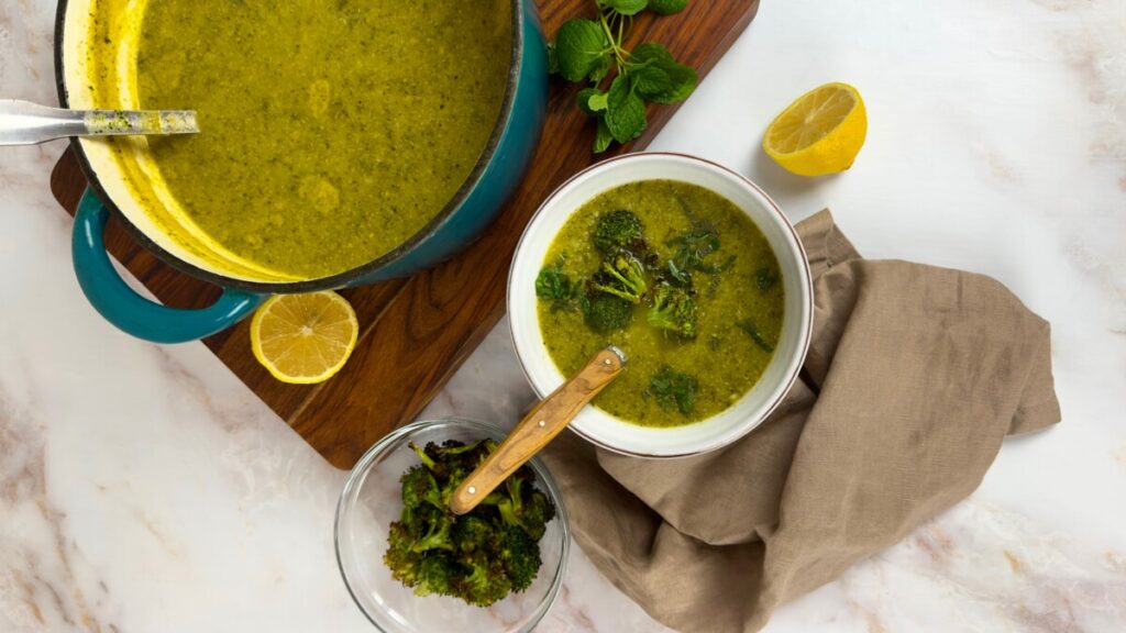 Bowl of creamy vegan broccoli soup, garnished with herbs.