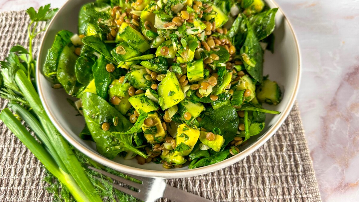 A vibrant bowl of Baby Spinach and Lentil Salad, garnished with fresh herbs and a light dressing.