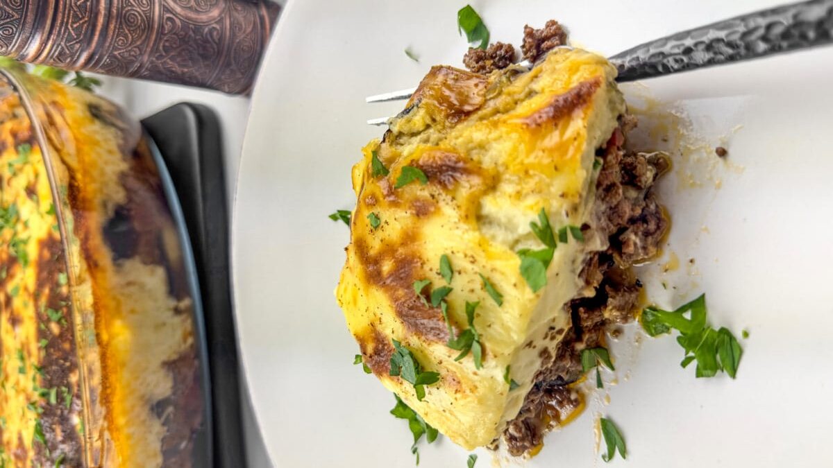 A slice of Traditional Greek Moussaka is a quintessential dish in Greek cuisine, a beloved classic that layers sautéed eggplant with spiced ground meat, often lamb or beef, all smothered under a velvety béchamel sauce