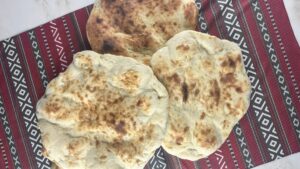 Freshly baked homemade taboon bread on a wooden cutting board