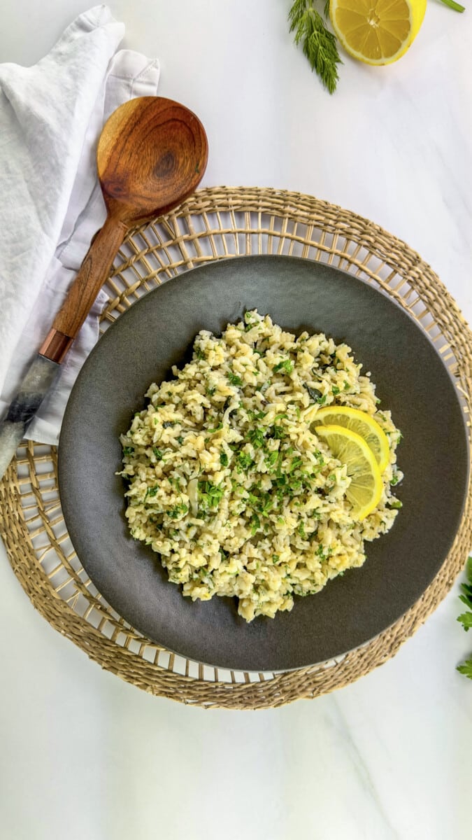 Fresh herb risotto served in a white bowl, garnished with fresh herbs and Parmesan cheese.