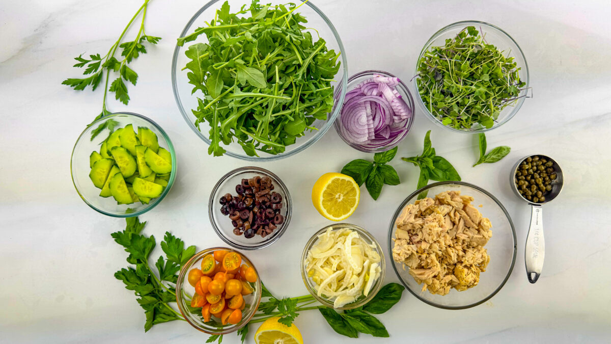 A variety of fresh ingredients laid out on a kitchen counter, ready for the preparation of a Mediterranean Tuna Salad.