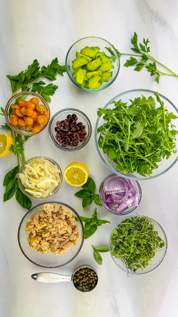 A variety of fresh ingredients laid out on a kitchen counter, ready for the preparation of a Mediterranean Tuna Salad.