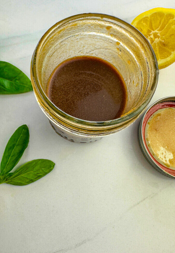 A small jar containing balsamic vinegar, olive oil, lemon juice, salt, and pepper whisked together to create a marinade.