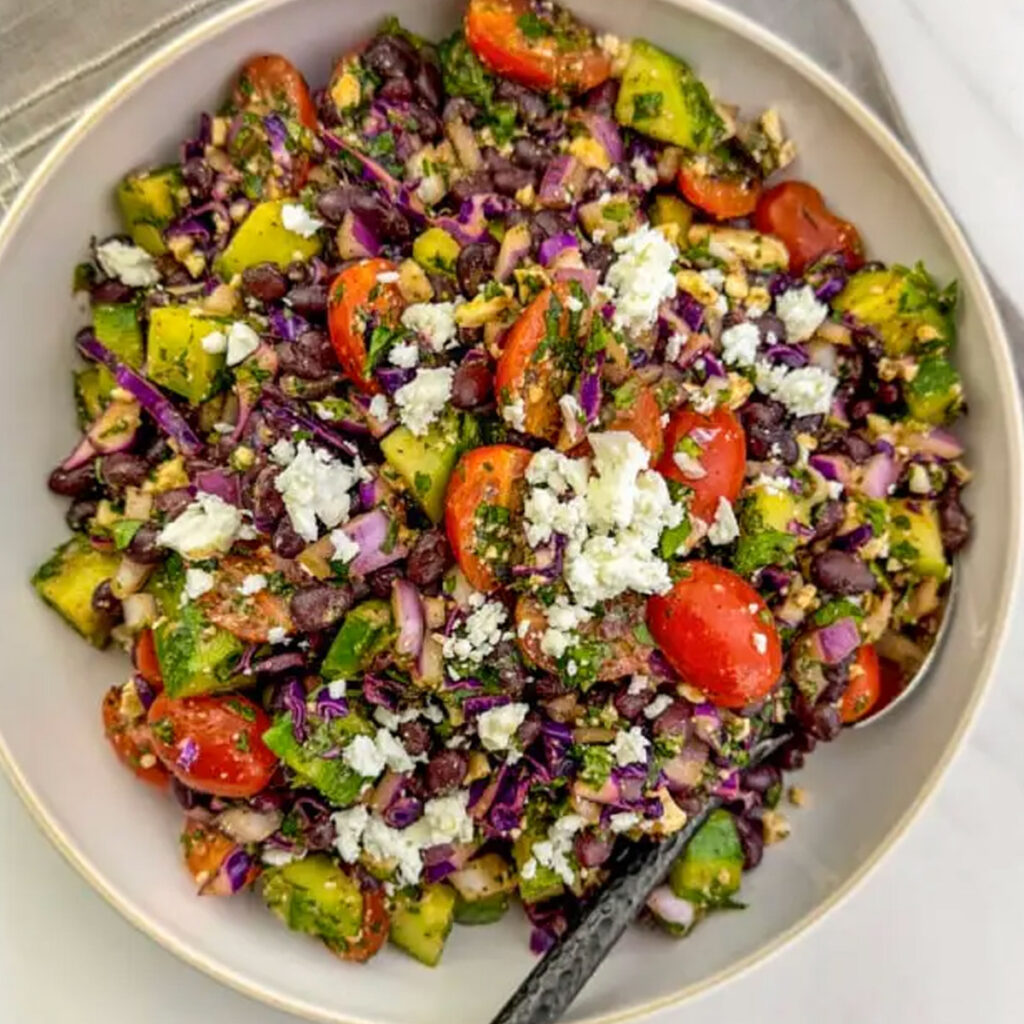 A colorful Mediterranean Black Bean Salad with tangy Pomegranate Molasses Dressing and Sumac, featured in a roundup of 17 refreshing salad recipes.