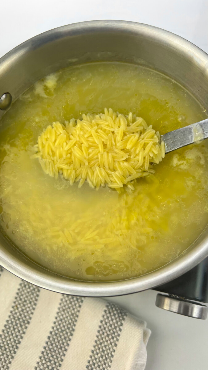 Large pot of boiling salted water with orzo pasta cooking until al dente.