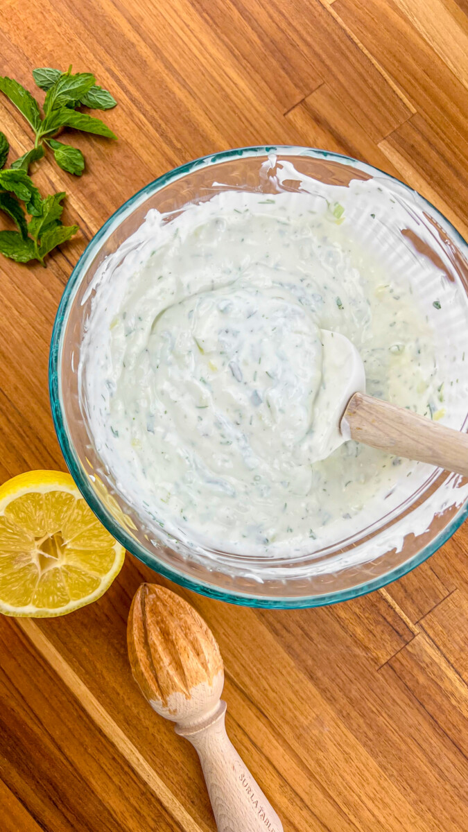 Mixing ingredients for tzatziki sauce in a bowl.