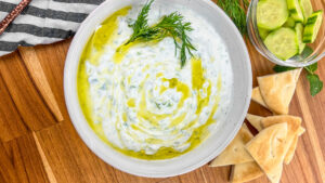 Finished tzatziki sauce served with pita bread and cucumber slices.