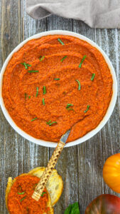 Freshly blended Romesco sauce being poured into a serving bowl.