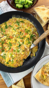 Sprinkling remaining shredded halloumi cheese over eggs."