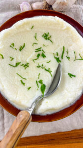 Finished Lebanese Garlic Sauce Toum in a bowl, garnished with a sprinkle of parsley.