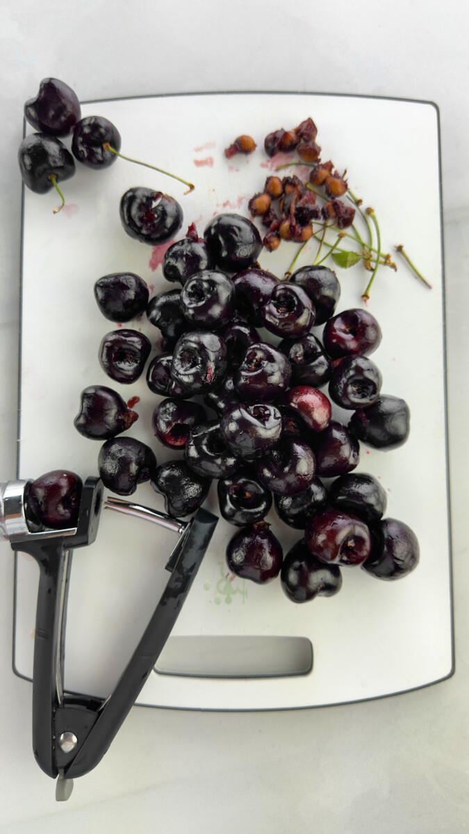 Using a cherry pitter tool to remove pits from fresh cherries.