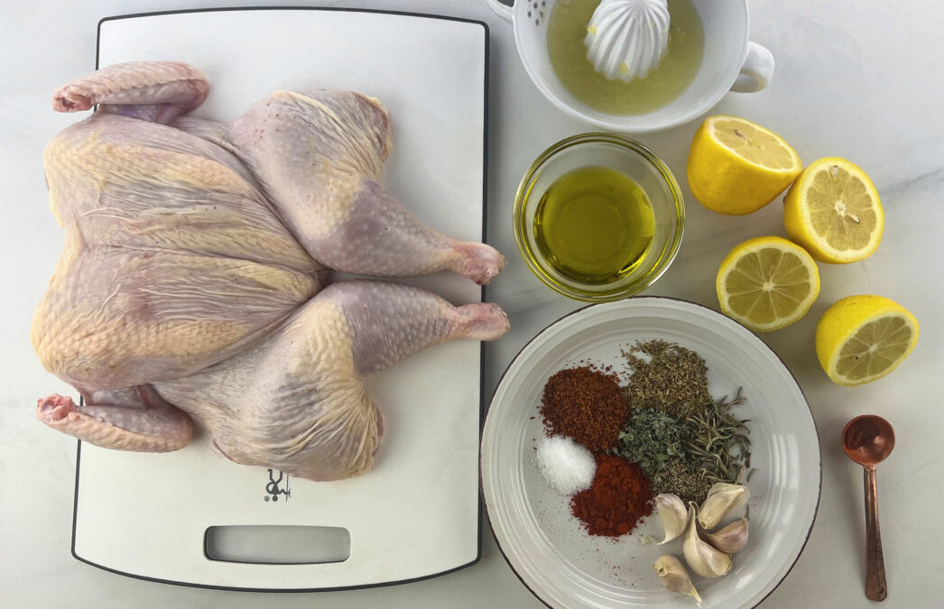 Cleaned and dried chicken on a countertop with an array of marinating ingredients beside it.