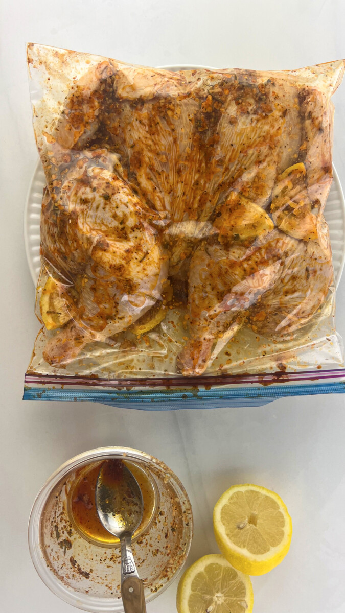 A ziplock bag containing a chicken fully immersed in marinade, set to soak in the flavors.