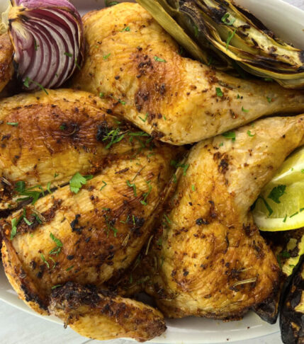 A beautifully plated roasted chicken accompanied by an assortment of grilled vegetables, ready to be served.