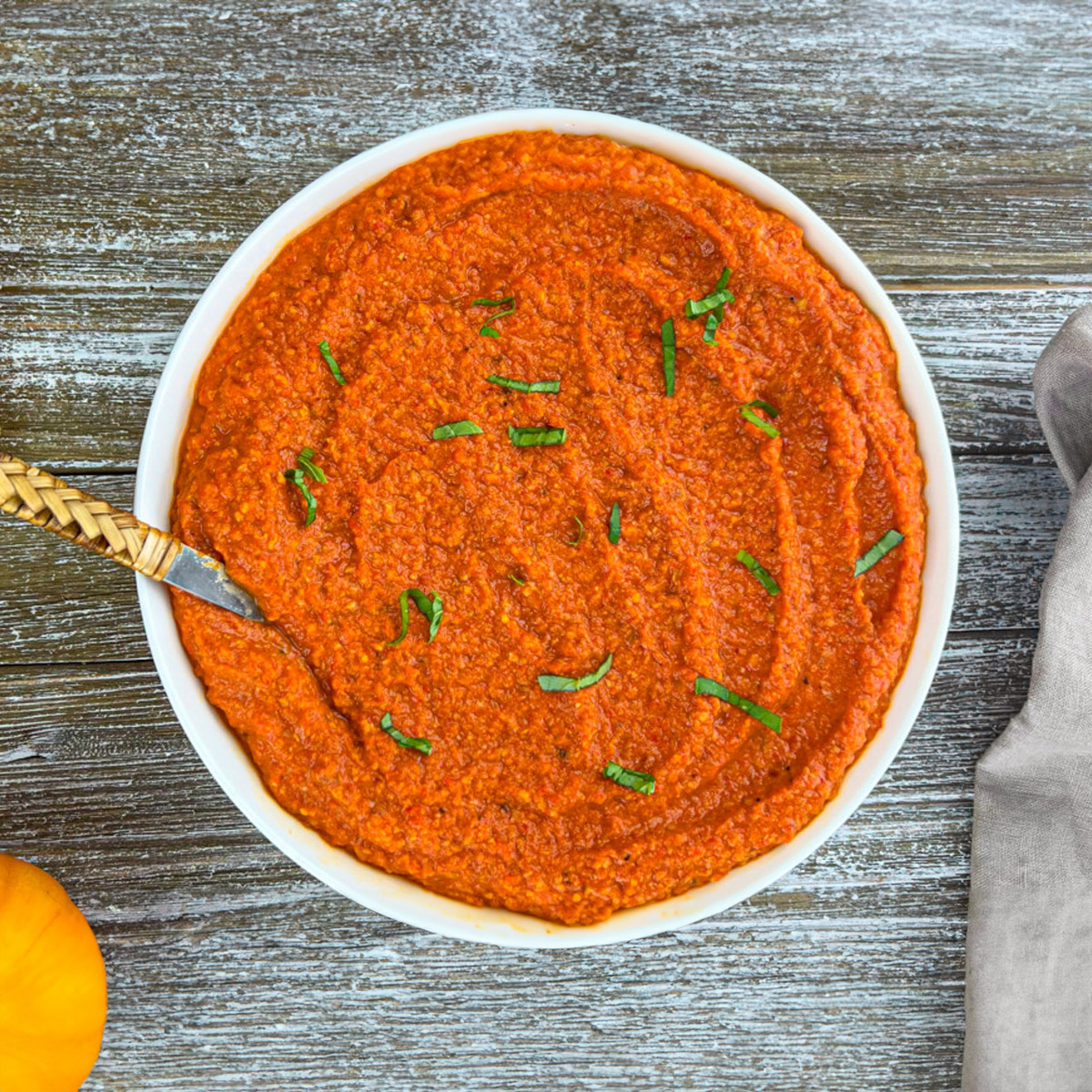 Freshly blended Romesco sauce being poured into a serving bowl.