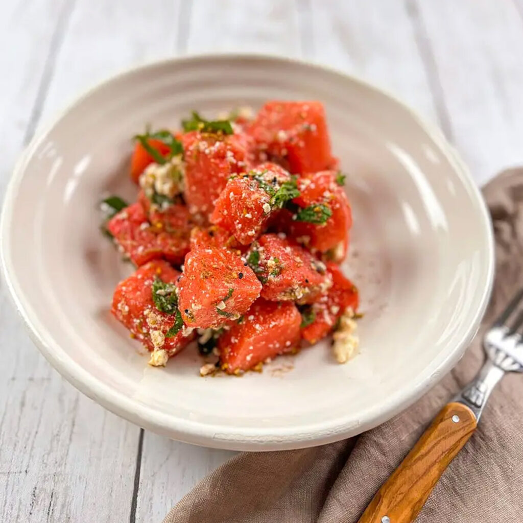Bowl of Watermelon Salad with Dukkha Feta Cheese and Mint, a refreshing and unique Mediterranean salad featured in a roundup of 17 invigorating salads.