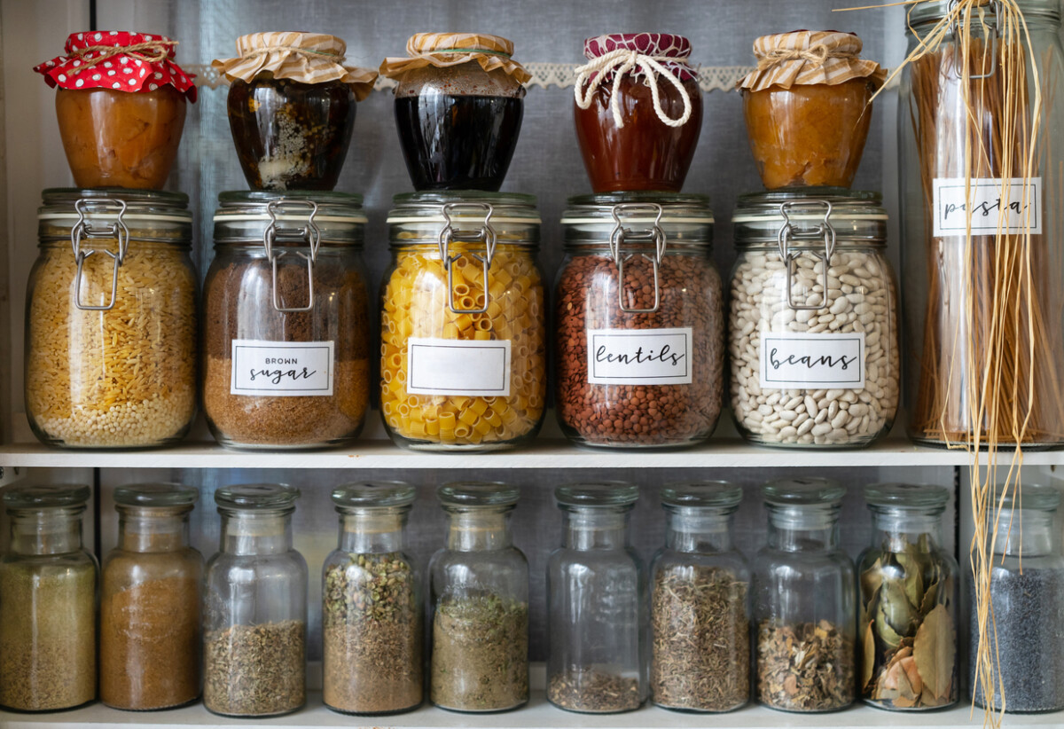 Mediterranean pantry shelves stocked with jars of dry herbs and legumes.