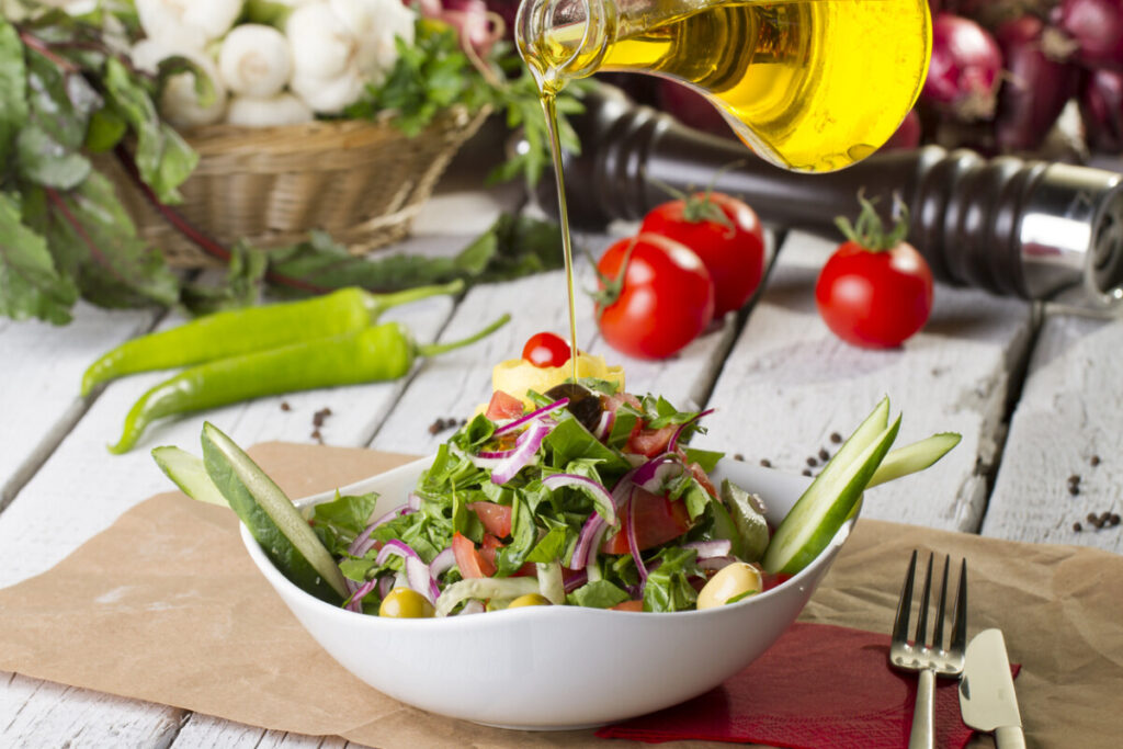 Drizzling golden olive oil over a fresh bowl of salad.