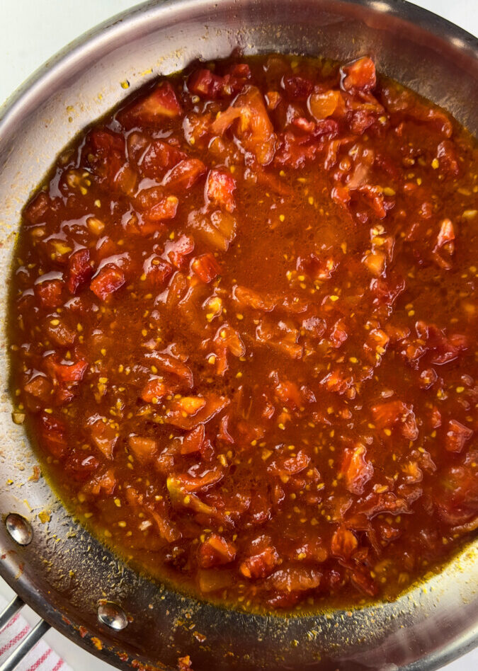 Tomato sauce simmering in a large skillet for Pasta alla Norma recipe.