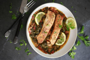 Plated Garlic Butter Salmon with lemon slices and fresh basil garnish.