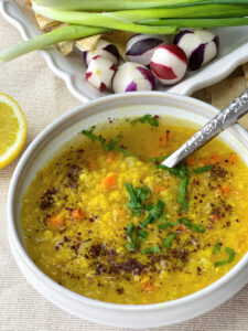 Steaming bowls of Egyptian Lentil Soup, adorned with fresh parsley, sumac, and lemon wedges
