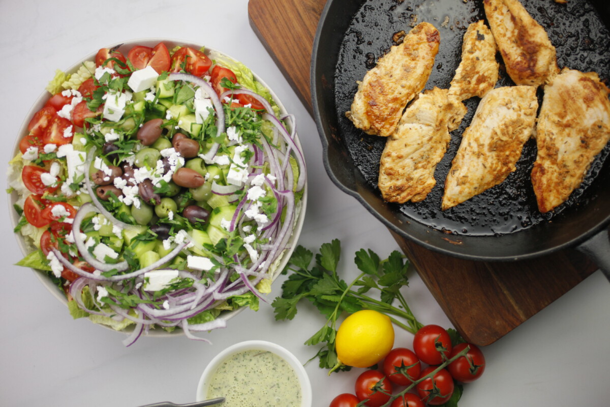 Vibrant salad greens fill a bowl, ready to be tossed with grilled chicken and Mediterranean flavors.