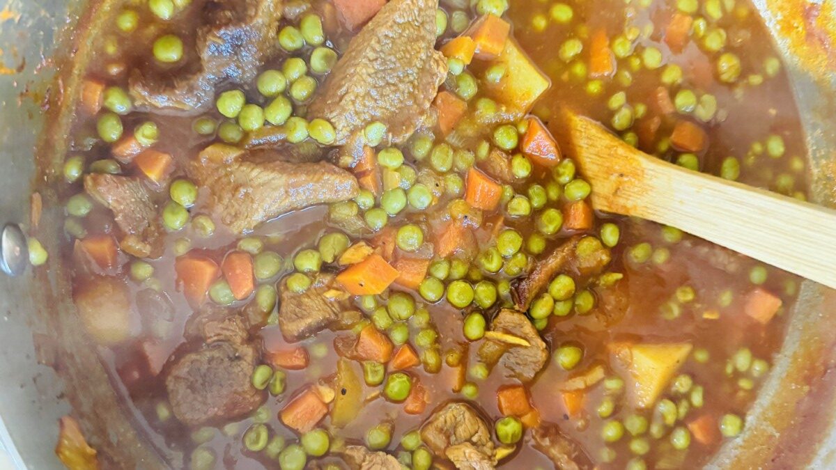 Beef chunks, peas, and tomato sauce simmering together in the pot