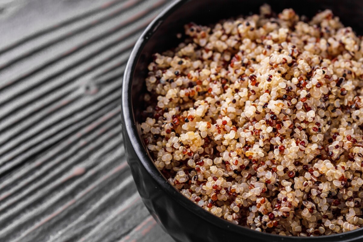 Bowl of healthy quinoa on a dark wooden rustic background cooked ready to use in the quinoa salad.